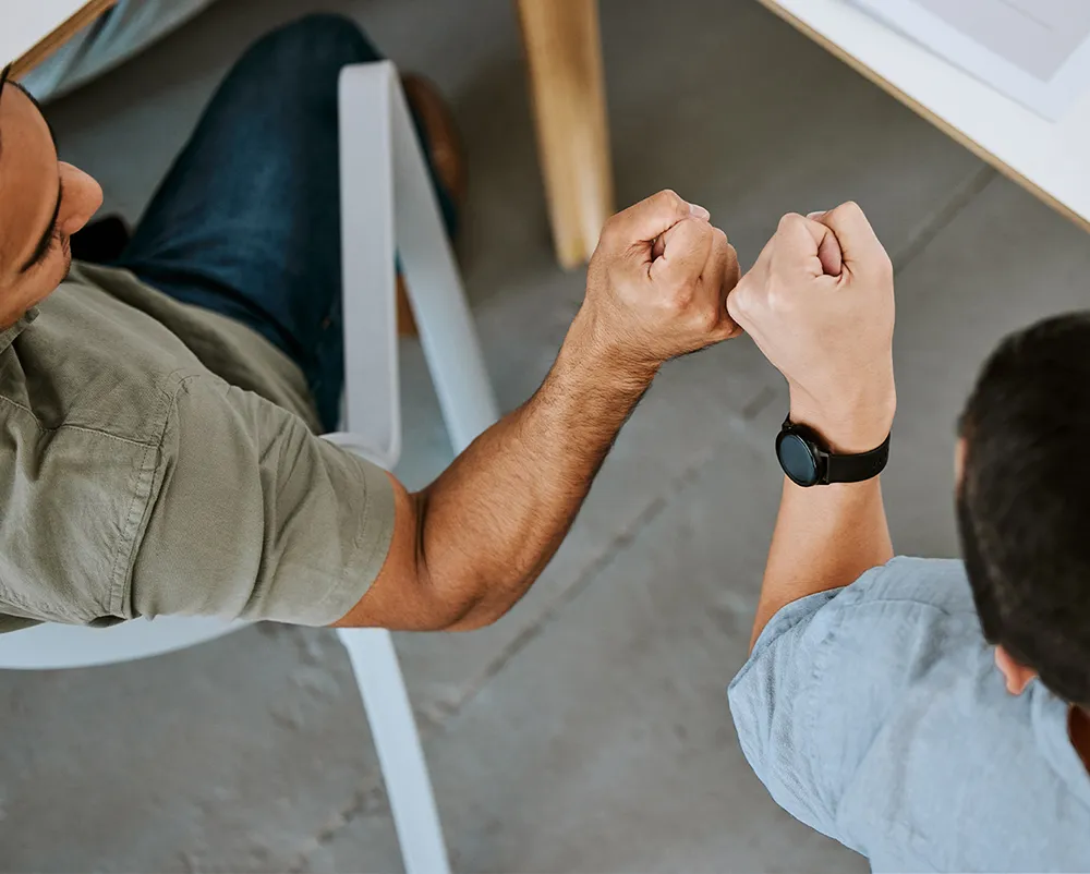 Two men bumping fists in office