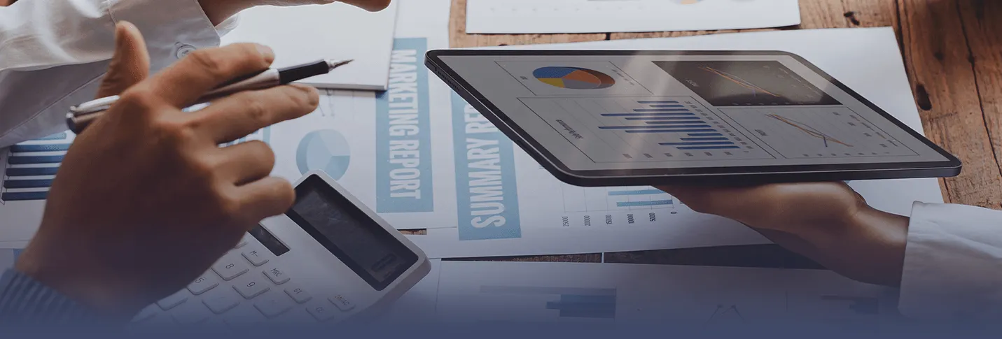 Two people in office with charts, calculator, and tablet